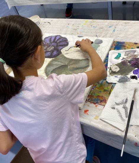 Kind arbeitet konzentriert an einem farbigen Kunstwerk im Atelier
